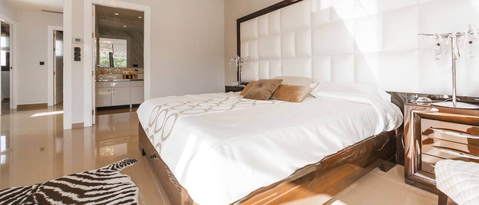 a look into a modern bedroom with white headboard and bronze furnishing l renovate site